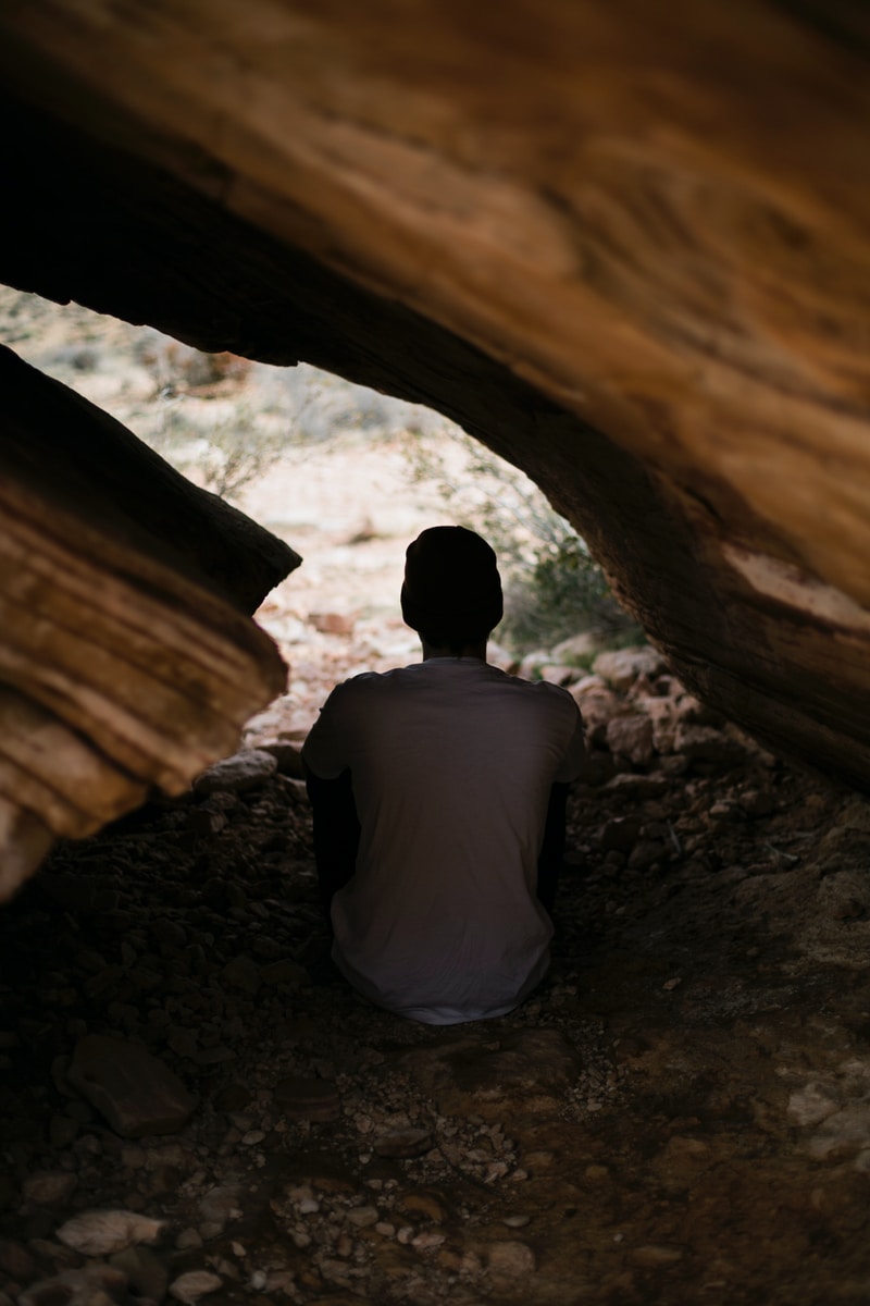 man in white shirt sitting inside cave
